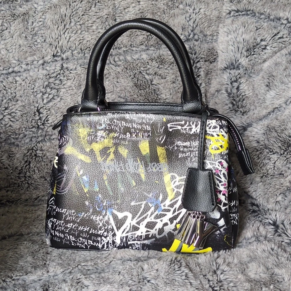 DKNY Paige small satchel crossbody handbag with a graffiti print.​